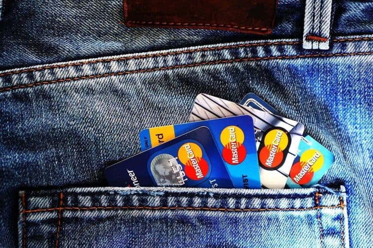 Several credit cards are sticking out of the back pocket of a pair of blue denim jeans.